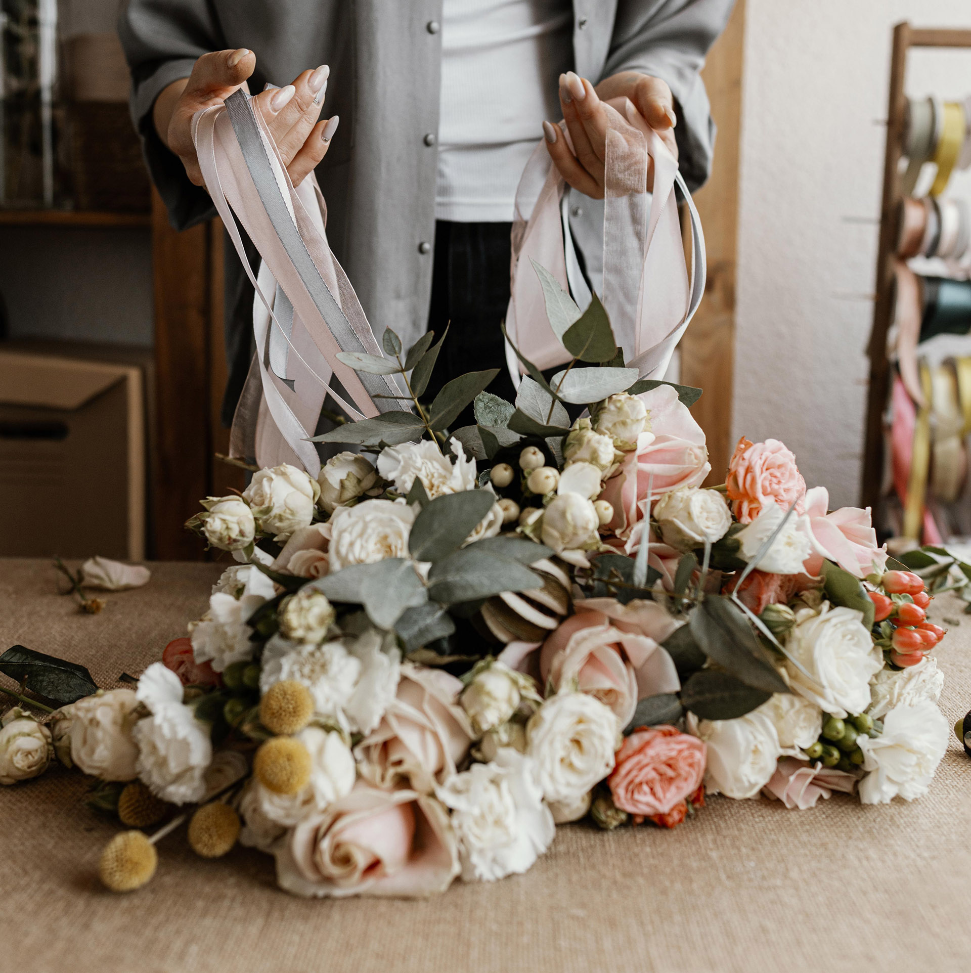 person holding ribbons and floral display of flowers on table